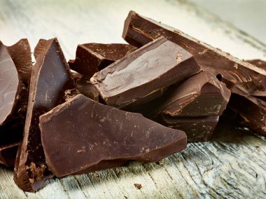 Tahta arka planda çikolata parçalarını kapat