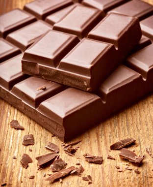 Tahta arka planda çikolata parçalarını kapat