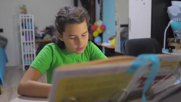 Niña pequeña hija hacer deberes estilo de vida educación lección escuela. vídeo en cámara lenta. preparación, de vuelta a la escuela. Una niña estudia con un libro. escuela niños familia concepto educación — Vídeos de Stock