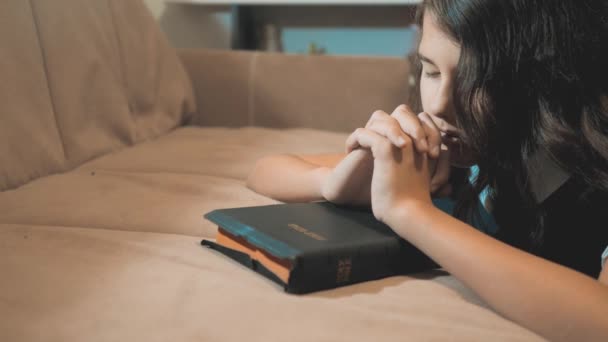 Fetiţa se roagă noaptea. Mâna fetiţei se roagă. Sfânta Biblie se roagă cu Biblia în mâinile ei. Catolicismul este un stil de viață sacru - Sfânta Biblie. Copiii și religia educând credința — Videoclip de stoc