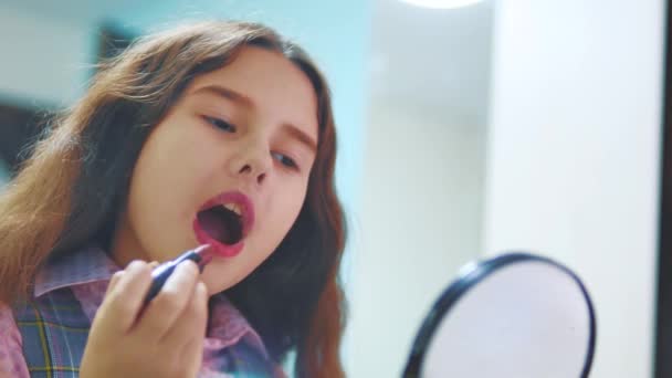 Urocza dziewczynka gra make up. Szczęśliwe dziecko malowanie jej usta. mała dziewczynka maluje usta patrząc w lustro. mała dziewczynka i szminka koncepcja tworzą styl życia — Wideo stockowe