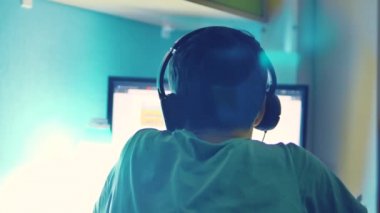 Genç çocuk bilgisayarda kulaklık izleyicisi'nde internet üzerinden online oyun oynuyor. Genç adam, geceleri bir video oyunu oynar. Genç çocuk ve bilgisayar yaşam tarzı kavramı
