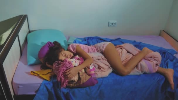 Adorável menina dormir no sofá-cama e abraçar sua boneca. menina morena dormindo à noite na cama querida infância. conceito de sono de estilo de vida infantil — Vídeo de Stock