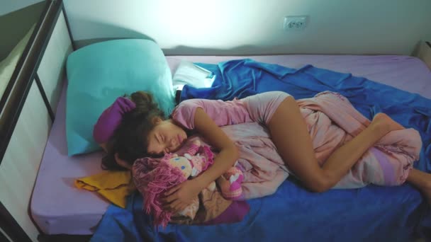 Adorável menina dormir no sofá-cama e abraçar sua boneca. menina morena dormindo à noite na cama querida infância. conceito de estilo de vida sono crianças — Vídeo de Stock