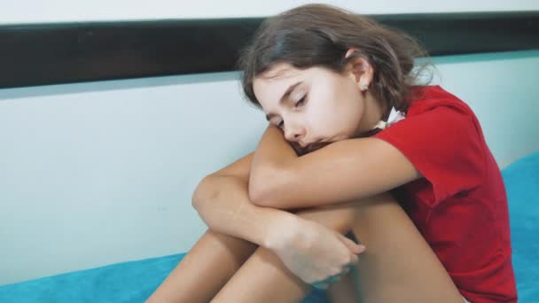 Грустная и подавленная маленькая девочка сидит грустная на кровати домашнего насилия. девочки грустные эмоции. маленькая девочка испытывает страдания концепция образа жизни — стоковое видео