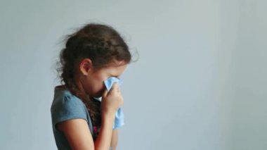 kız çocuk gri bir arka plan üzerinde mendil içine hapşırma. küçük kız soğuk olsun ve burnu havaya. Genç kız soğuk grip kavramı yaşam tarzı