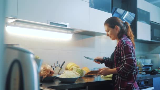 životní styl žena v kuchyni připravovat jídlo koncept. dívka v kuchyni škrty zelí s nožem. Cook Bezmasá jídla zdravé jídlo. dívka doma v kuchyni zpomalené video