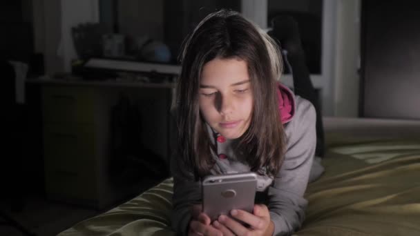 Teenage girl online shopping looks on her smartphone in bed during the night. little teen hood girl writes lifestyle a message chatting in social media messenger night evening indoors smartphone on