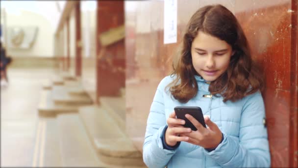 dívčí teenager v podzemní dráze metra v metru, čekající na příjezd vlaku, má životní styl smartphone. malá holčička bruneta dcera prohledá Internet na webových sociálních sítích.