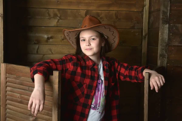 木製の壁の背景に赤の格子縞シャツ若い女の子のカウボーイ — ストック写真