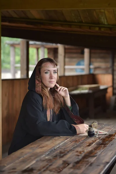 中世のマントの女性ペンで座っているし 書き込みます — ストック写真