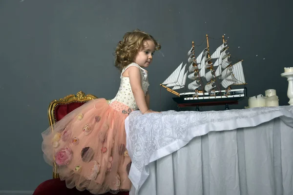 グッズ ヨット レトロなスタイルの写真をテーブルに座っているピンクのドレスでエレガントな白の魅力的な少女 — ストック写真