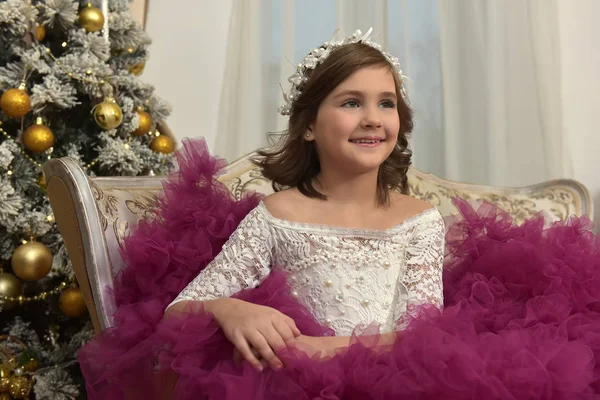 クリスマスの装飾で部屋のソファの上に座っているブルゴーニュのドレスでシックな白いドレスの女の子 — ストック写真