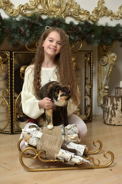 クリスマスの暖炉のそばで彼女の腕で猫と女の子子供 — ストック写真