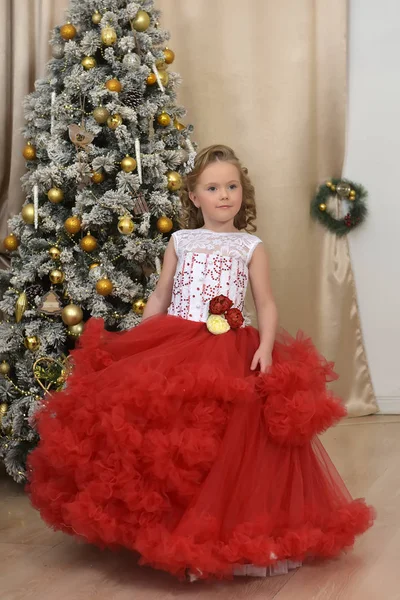 美丽的女孩跳舞在红色与白色礼服在圣诞节由圣诞树 — 图库照片