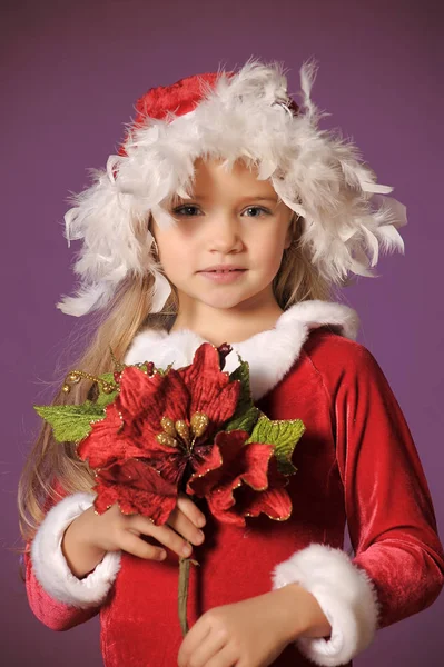 一个美丽的金发女孩的肖像在圣诞帽子与圣诞花束 — 图库照片