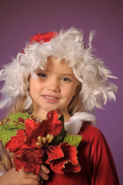 一个美丽的金发女孩的肖像在圣诞帽子与圣诞花束 — 图库照片