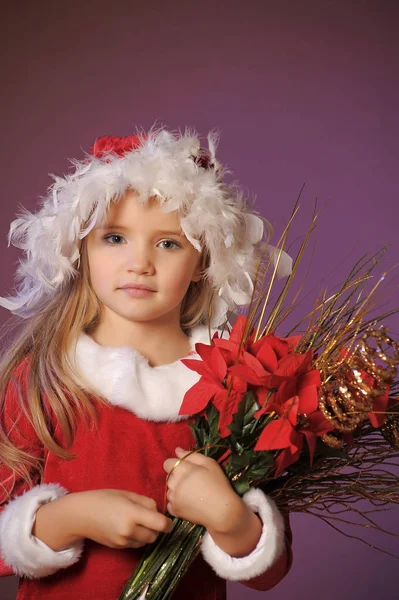 クリスマスの花束とクリスマスの帽子の美しい金髪の少女の肖像画 — ストック写真