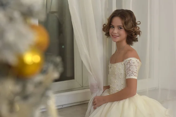 クリスマスの手での窓の白いドレスで美しい少女 — ストック写真
