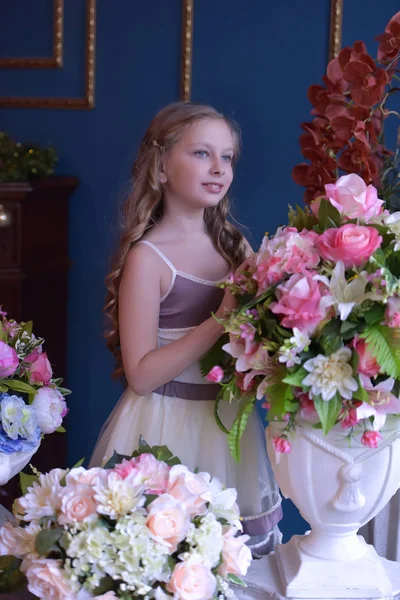 花の花瓶の横にある美しいドレスを着た女の子 — ストック写真