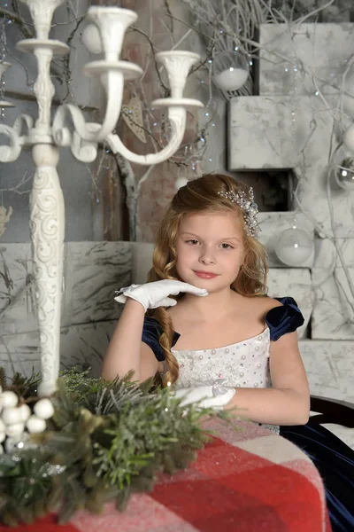 美丽的金发碧眼的卷发在蓝色礼服坐在一张桌子在圣诞节 — 图库照片