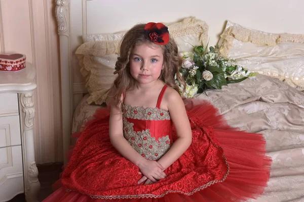 赤いドレスと帽子 ソファーに座っていた小さな女の子王女の肖像 — ストック写真