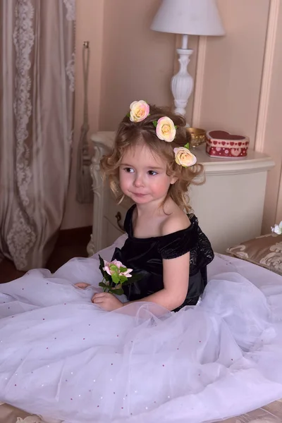 可爱的小女孩与她的头上的花冠和她手中的鲜花 — 图库照片