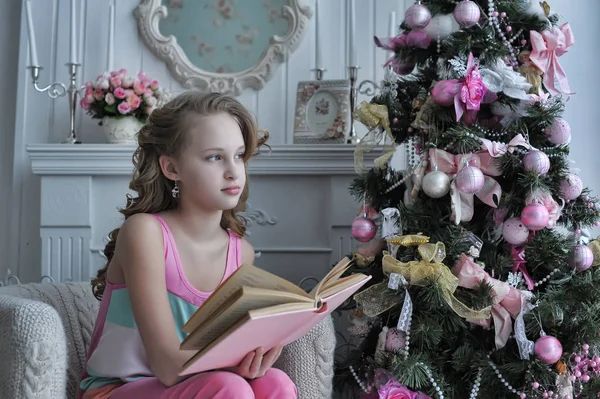 在圣诞树上粉红色的女孩与一本书在圣诞节 — 图库照片