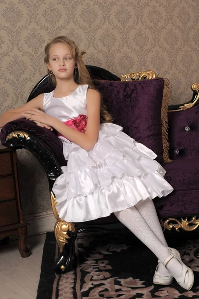 坐在天鹅绒沙发上的美丽优雅的女孩白色礼服 — 图库照片