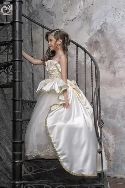 穿着白色雅致维多利亚时代服装的女孩在螺旋形楼梯上 — 图库照片