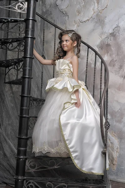 穿着白色雅致维多利亚时代服装的女孩在螺旋形楼梯上 — 图库照片