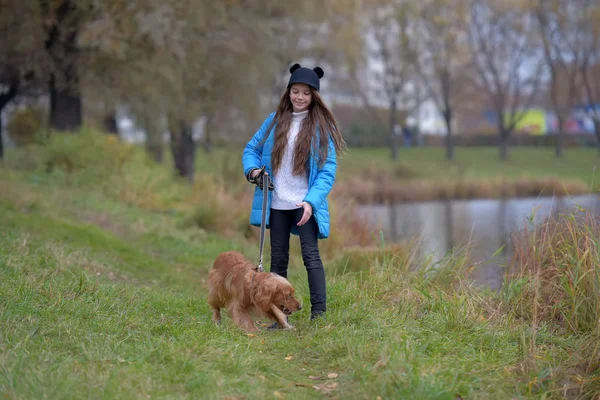 快乐的女孩在公园里与一只狗在秋天在湖边 — 图库照片