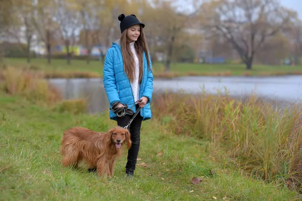 快乐的女孩在公园里与一只狗在秋天在湖边 — 图库照片
