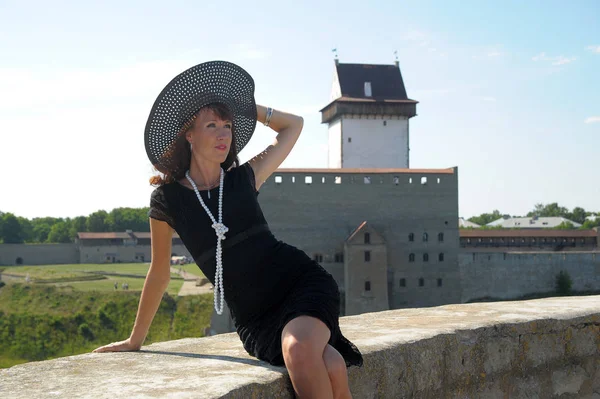 Γυναίκα Μαύρο Φόρεμα Και Καπέλο Στο Φόντο Ενός Μεσαιωνικού Φρουρίου — Φωτογραφία Αρχείου