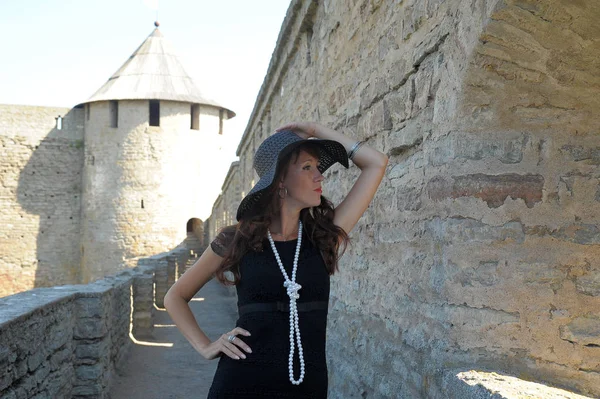 Γυναίκα Μαύρο Φόρεμα Και Καπέλο Στο Φόντο Ενός Μεσαιωνικού Φρουρίου — Φωτογραφία Αρχείου