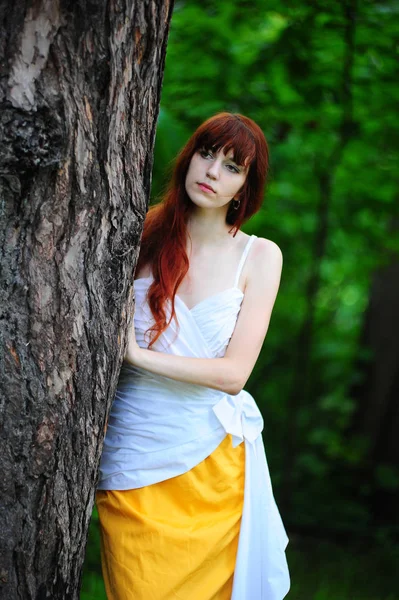 红头发的女孩在白色与黄色的晚礼服的树 — 图库照片