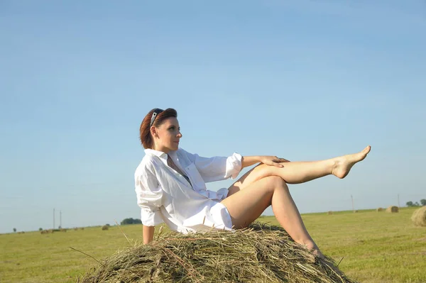 夏畑の干し草の上に白いシャツを持った女性 — ストック写真