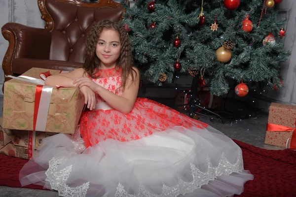 女孩在白色与红色礼服在圣诞树与礼物在圣诞节 — 图库照片