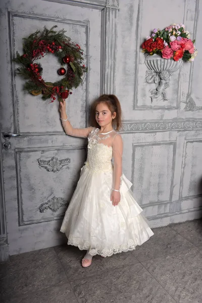 女孩在白色礼服旁边的圣诞节花圈门 — 图库照片