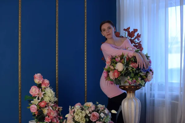 花の大きな花瓶の横にピンクの女 — ストック写真