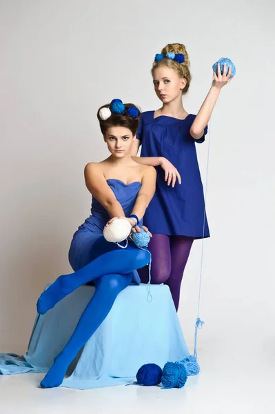 两个女孩在蓝色与羊毛球在他们的手中 在他们的头发 — 图库照片