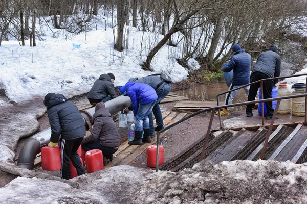 Människor som samlar vatten på en fjäder i burkar — Stockfoto