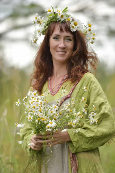 Frau im grünen Kleid mit einem Kranz aus Gänseblümchen im Haar und — Stockfoto