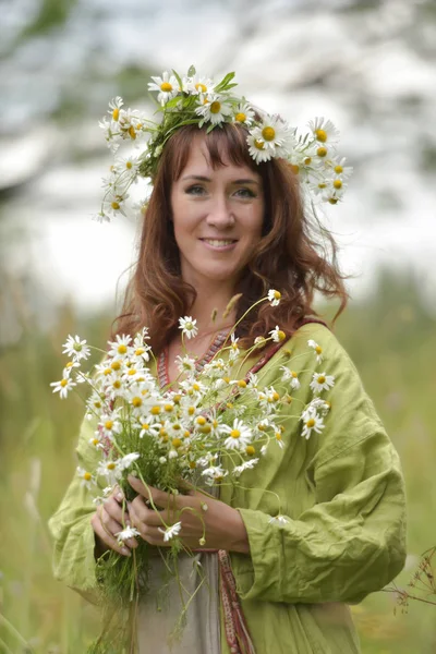 Mulher em um vestido verde com uma coroa de margaridas em seu cabelo e — Fotografia de Stock