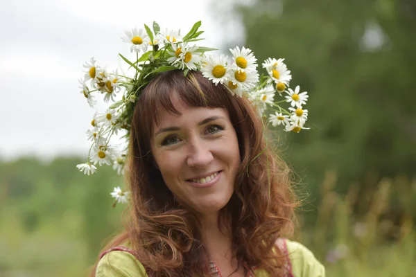 Mulher em um vestido verde com uma coroa de margaridas em seu cabelo e — Fotografia de Stock