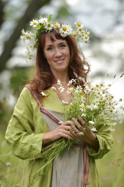 Mulher em um vestido verde com uma coroa de margaridas em seu cabelo e — Fotografia de Stock