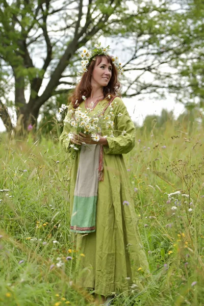 Donna in abito verde con una ghirlanda di margherite tra i capelli e — Foto Stock