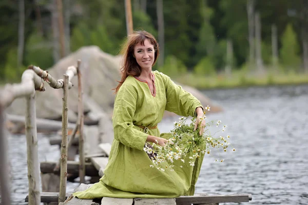 Frau am Wasser mit einem Kranz in der Hand — Stockfoto