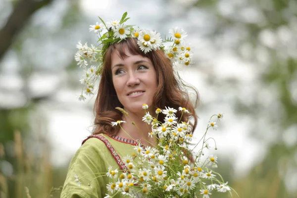 Mulher em um vestido verde com uma coroa de margaridas em seu cabelo e — Fotografia de Stock