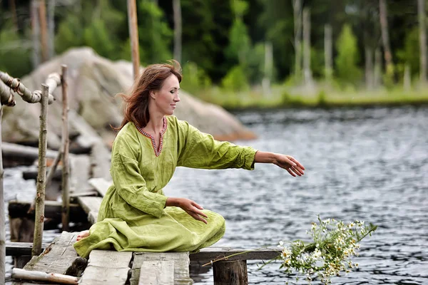Γυναίκα δίπλα στο νερό με ένα στεφάνι στα χέρια της — Φωτογραφία Αρχείου